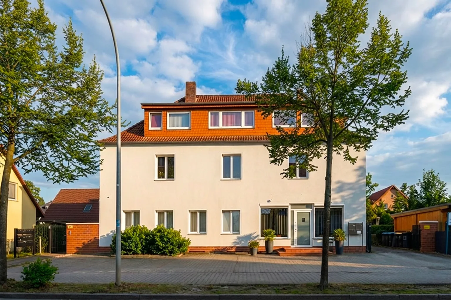Außenansicht eines weißen Hauses mit rotem Dach und Bäumen